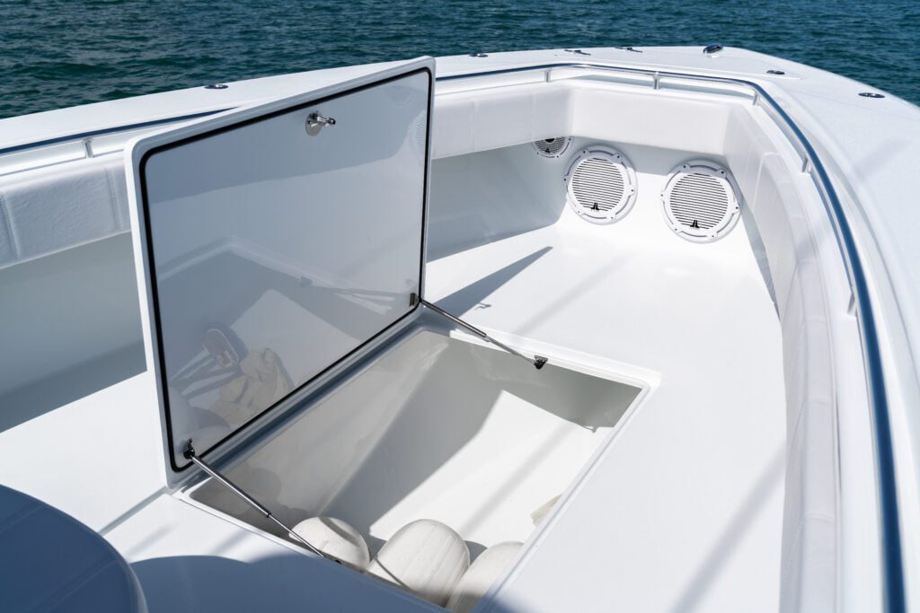 Opened storage compartment on a white boat's deck, revealing some white items inside; the boat is on a body of water.