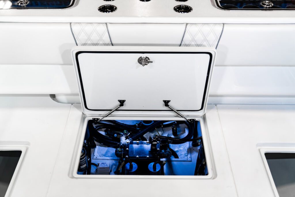 A boat hatch is open, revealing the engine components and various mechanical parts inside, illuminated by blue lighting.