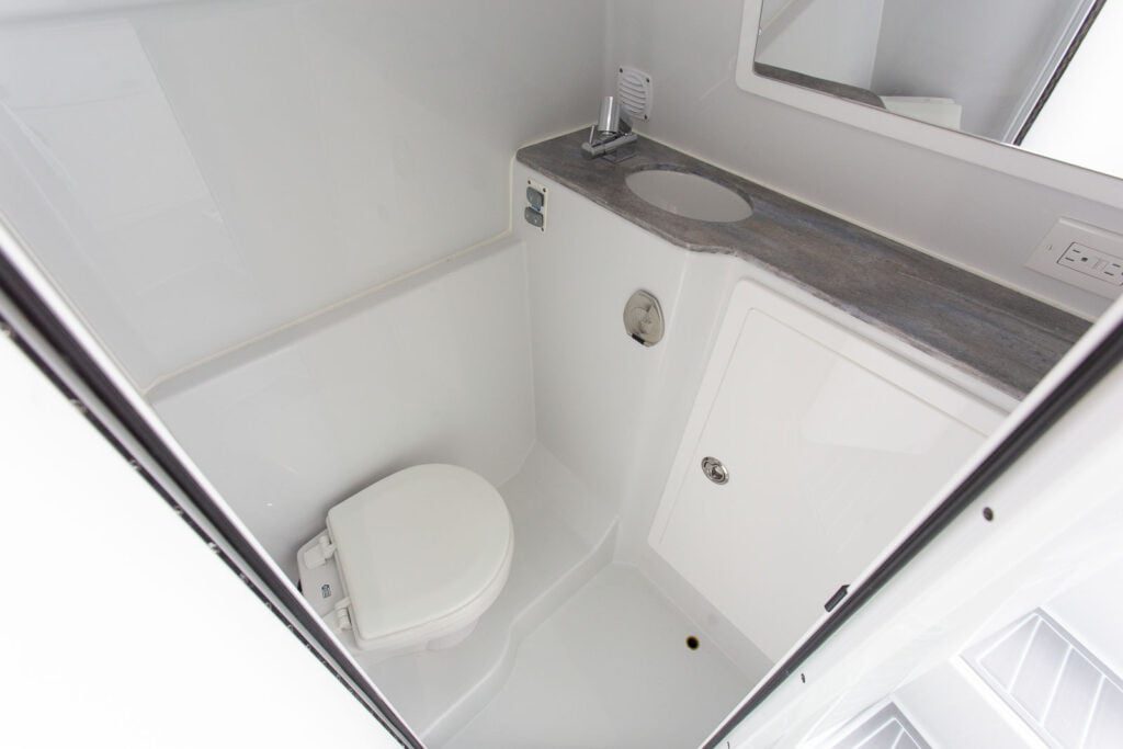 A compact, white bathroom with a toilet, sink, and mirror.
