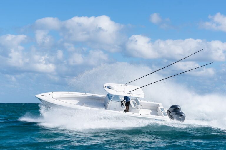 A white powerboat speeding through choppy waters with its bow raised, creating large splashes under a partly cloudy sky. Two extended fishing rods are visible at the back.