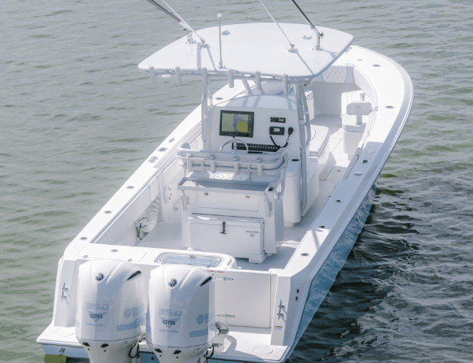 A white motorboat with dual outboard engines and navigational equipment on the console floating on calm water.