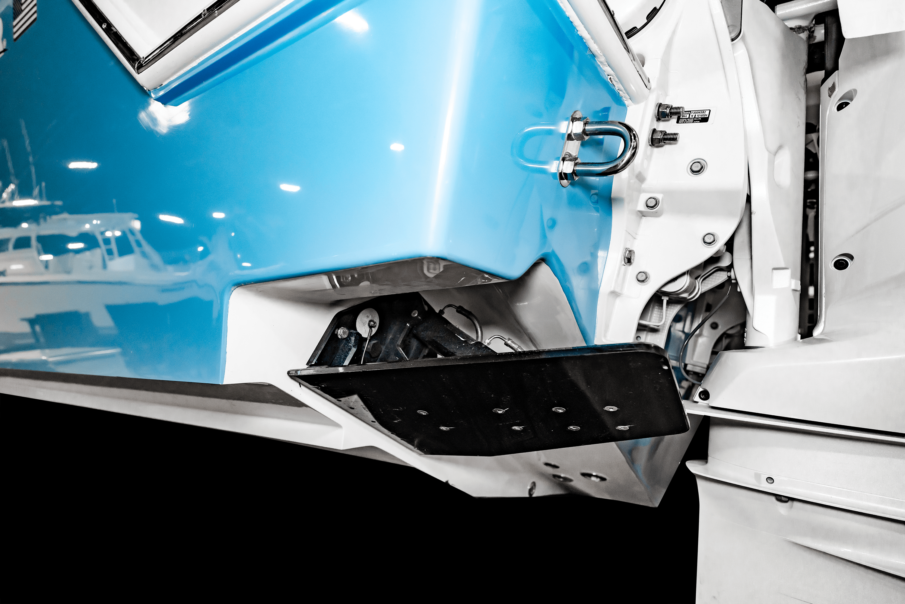 Close-up of a boat hull featuring a retracted trim tab on the underside, with a blue and white color scheme.