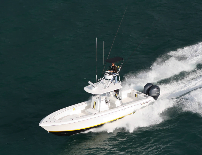 A speedboat with a raised control platform and dual outboard motors travels quickly across open water, leaving a wake.