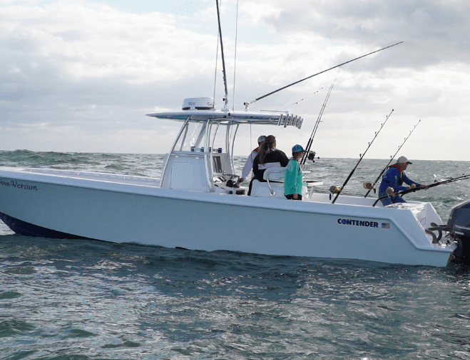 A group of people on a fishing boat named "Contender" on the water, with fishing rods extended over the side.