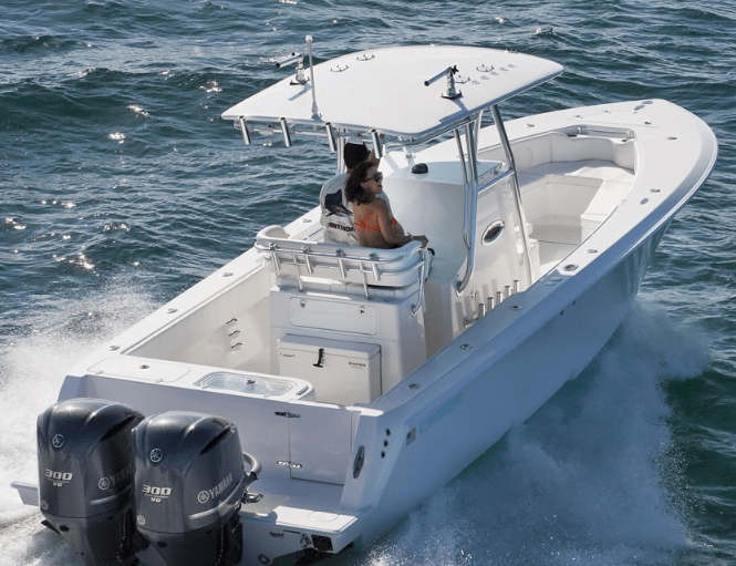Two people are on a white boat with twin outboard engines, navigating through the water.